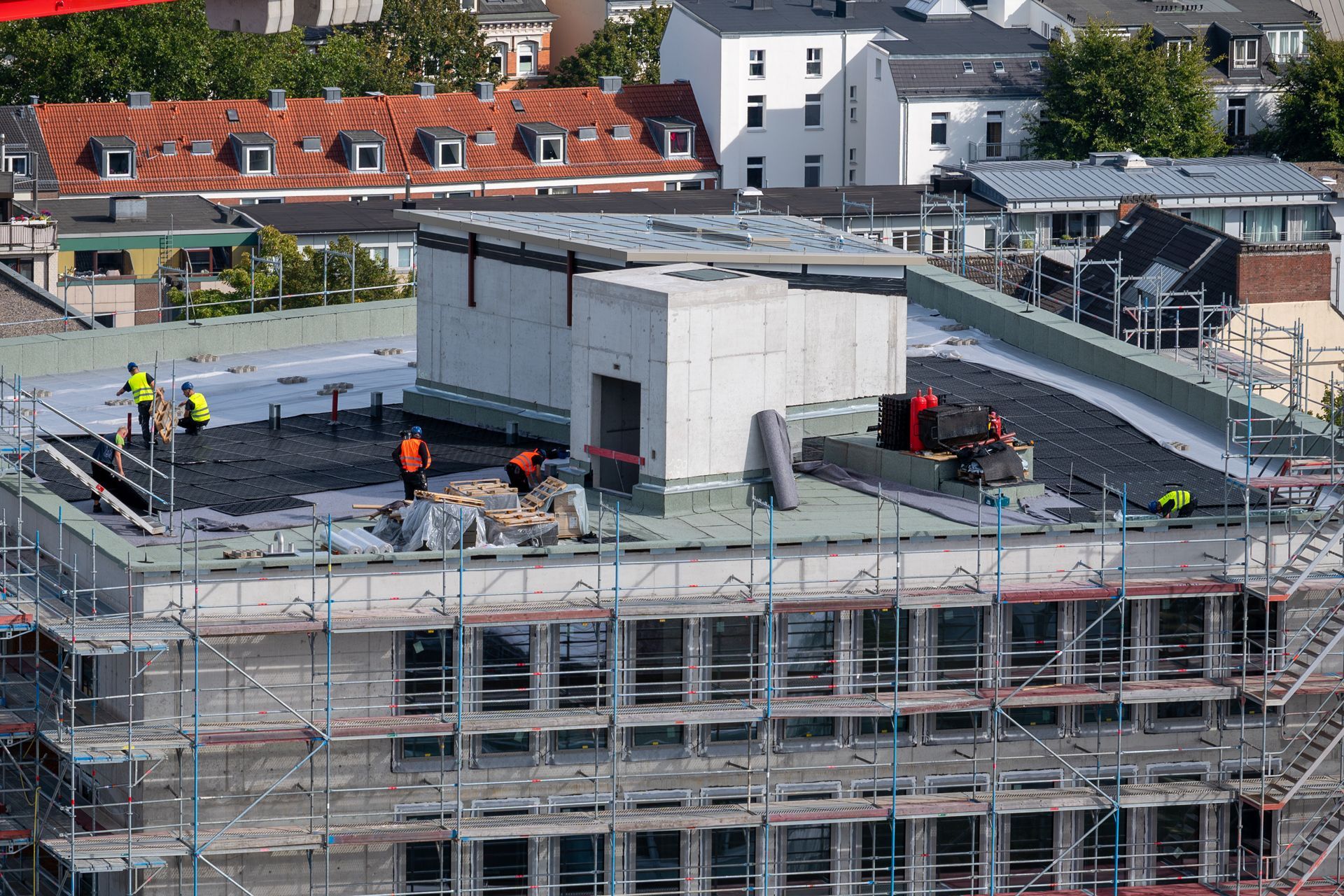 Crew installing materials on a commercial rooftop under construction. Crew installing materials on a commercial rooftop under construction.