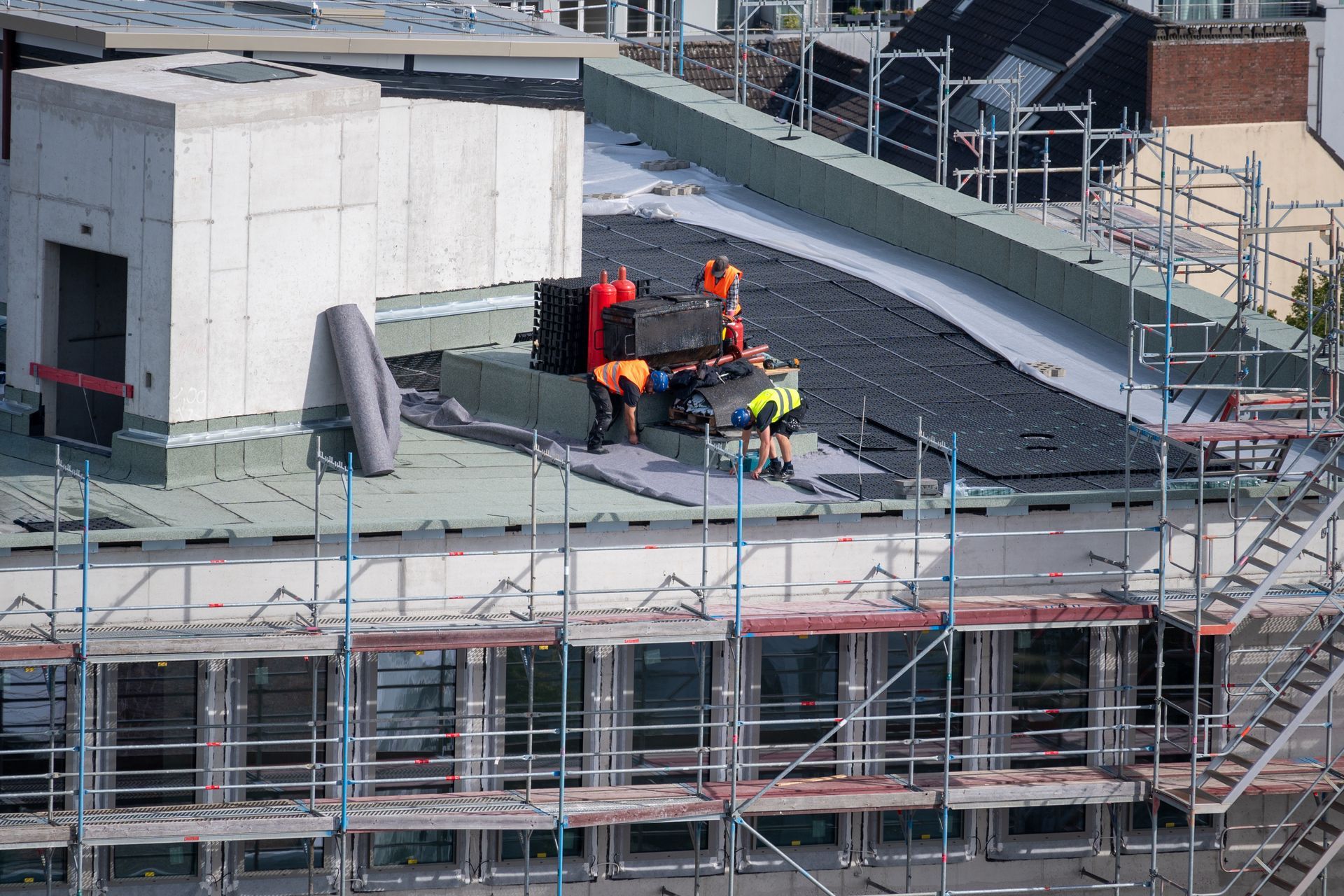 A commercial roofing crew is installing a waterproof membrane on a building roof. A commercial roofing crew is installing a waterproof membrane on a building roof.