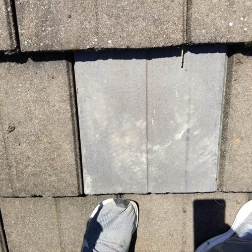 A person is standing on a concrete floor next to a brick wall.