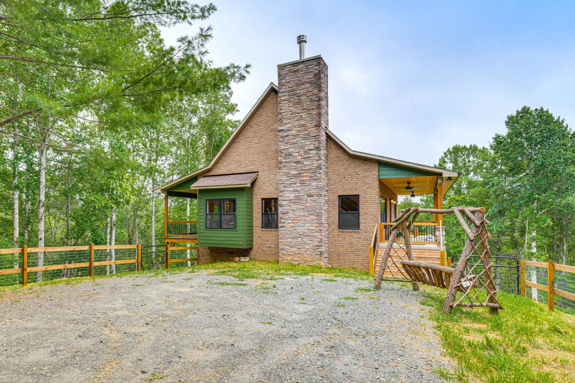 Wooden cabin beside a winding gravel road in a misty forested mountain setting