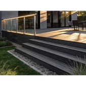 Wooden deck with black patio furniture beside a rustic cabin in a wooded setting.