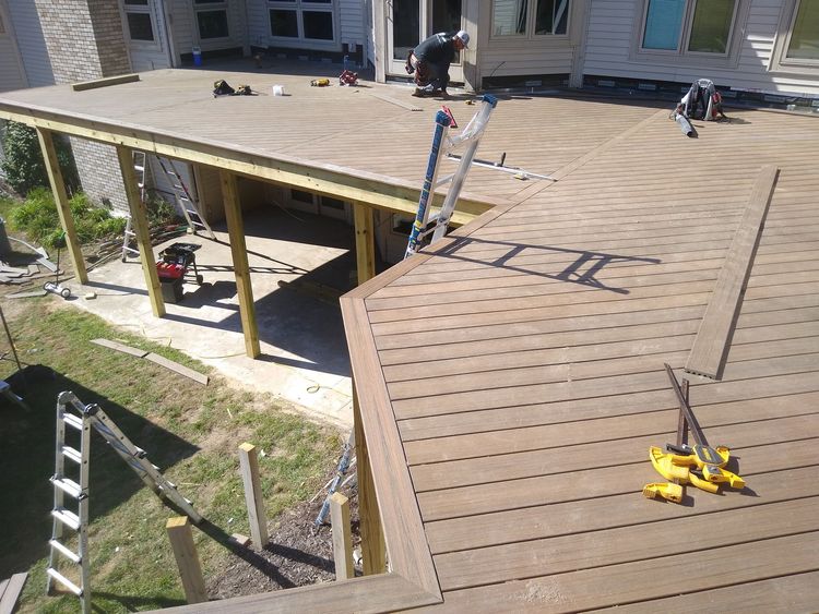 Roof under construction with ladders, tools, and workers on a plywood deck
