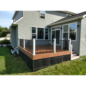 Back deck with wooden floor, black railings, and white posts on a beige house exterior