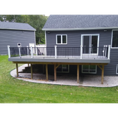 Raised deck on a gray house with black railing and white-trimmed sliding doors in a grassy yard.