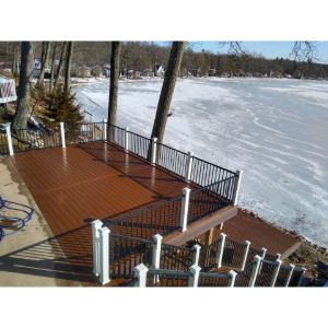 Wooden deck with black railings beside a frozen lake in winter