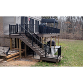 Raised backyard deck with black railings and stairs leading down to a grassy yard