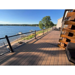 Lakeside wooden deck with black railings beside calm water on a sunny day