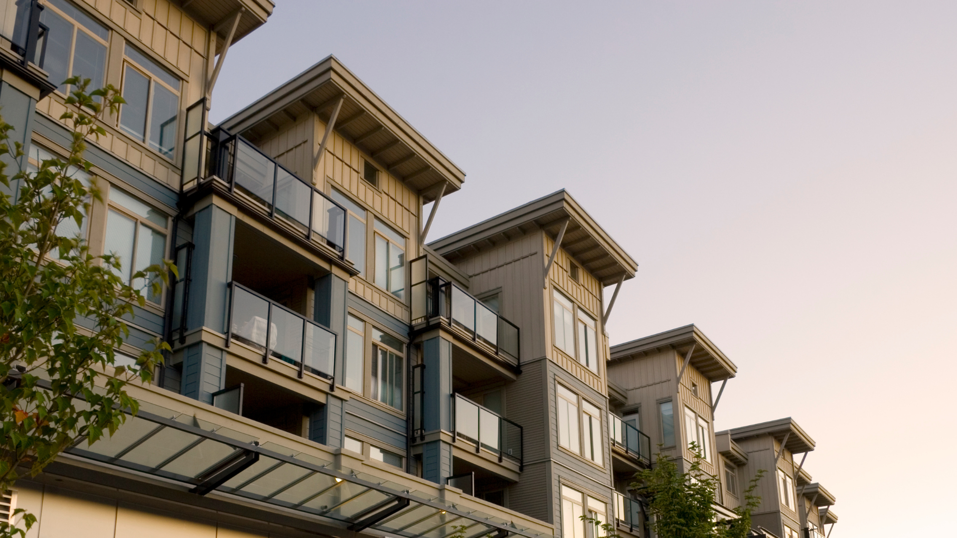 Modern apartment buildings with balconies against a pale sky at sunset