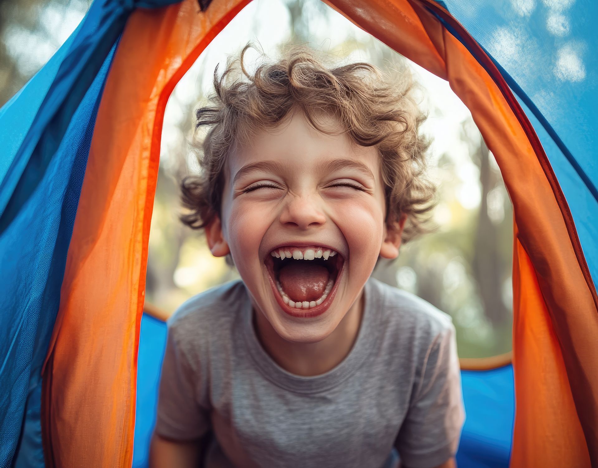 Smiling child laughing inside a colorful play tent, close-up.