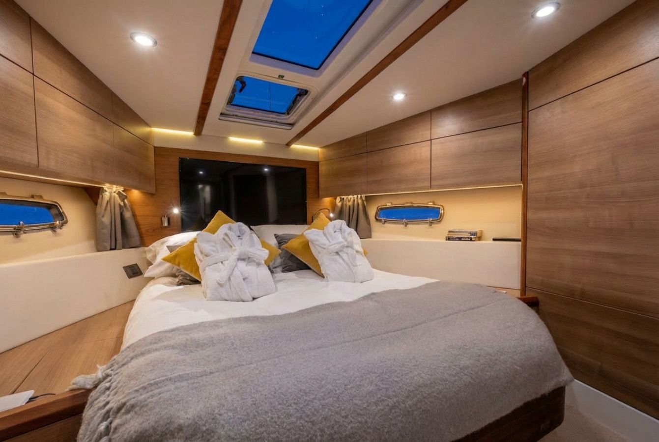 Modern cabin bedroom with a large bed, wood paneling, and blue skylight windows