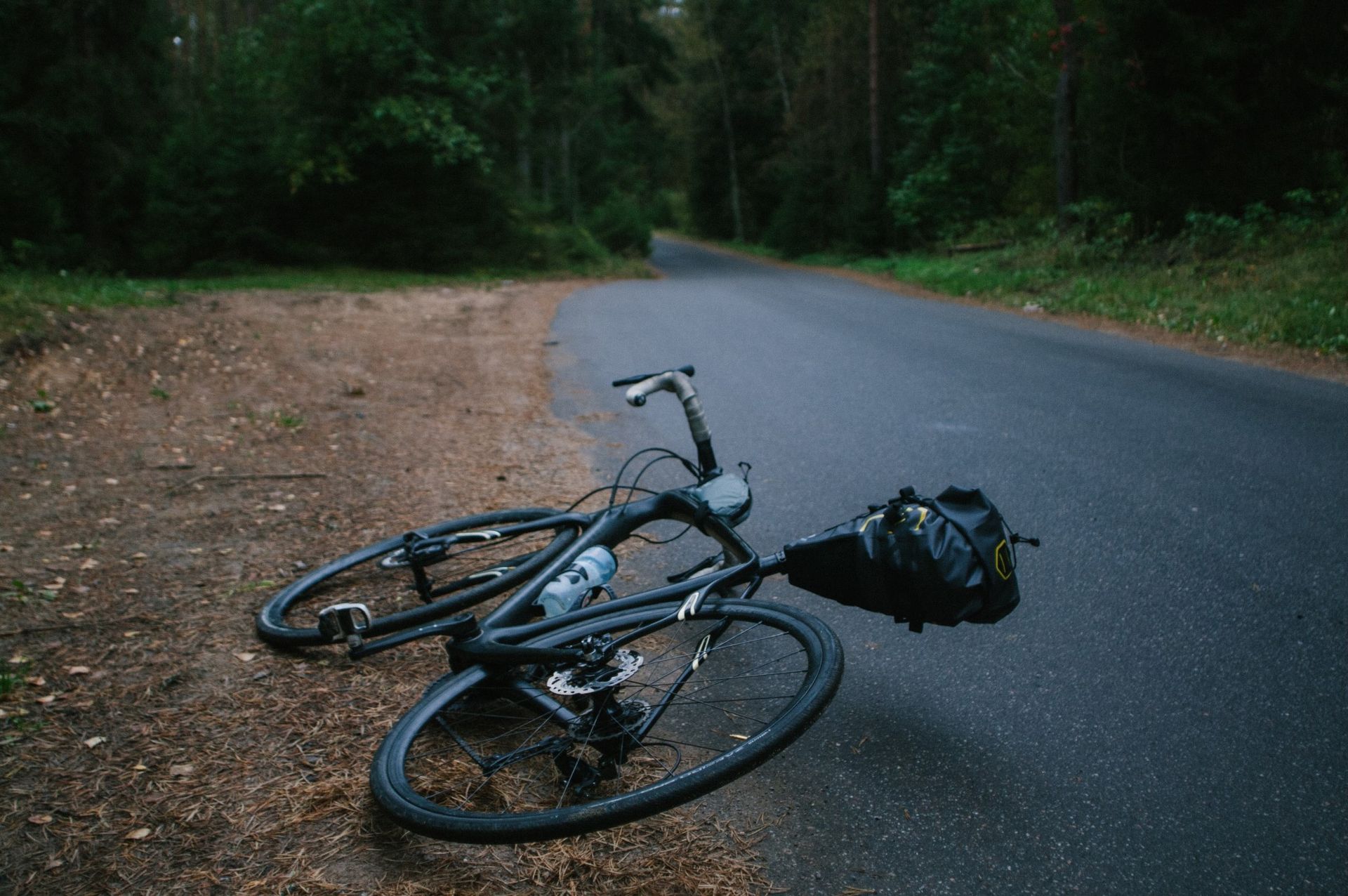 A bicycle is laying on its side on the side of a road.
