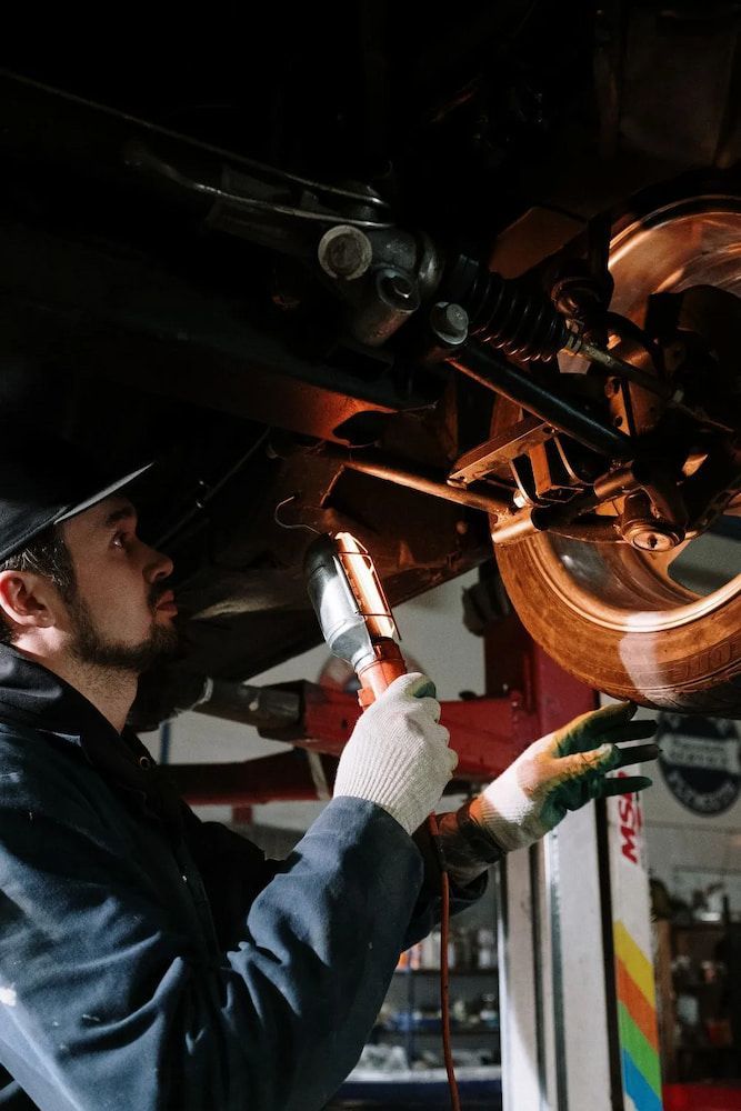 A Man Is Working Under A Car With A Flashlight — Figtree Brake and Clutch in Figtree, NSW