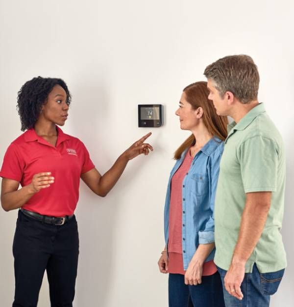 A woman in a red shirt is talking to two people