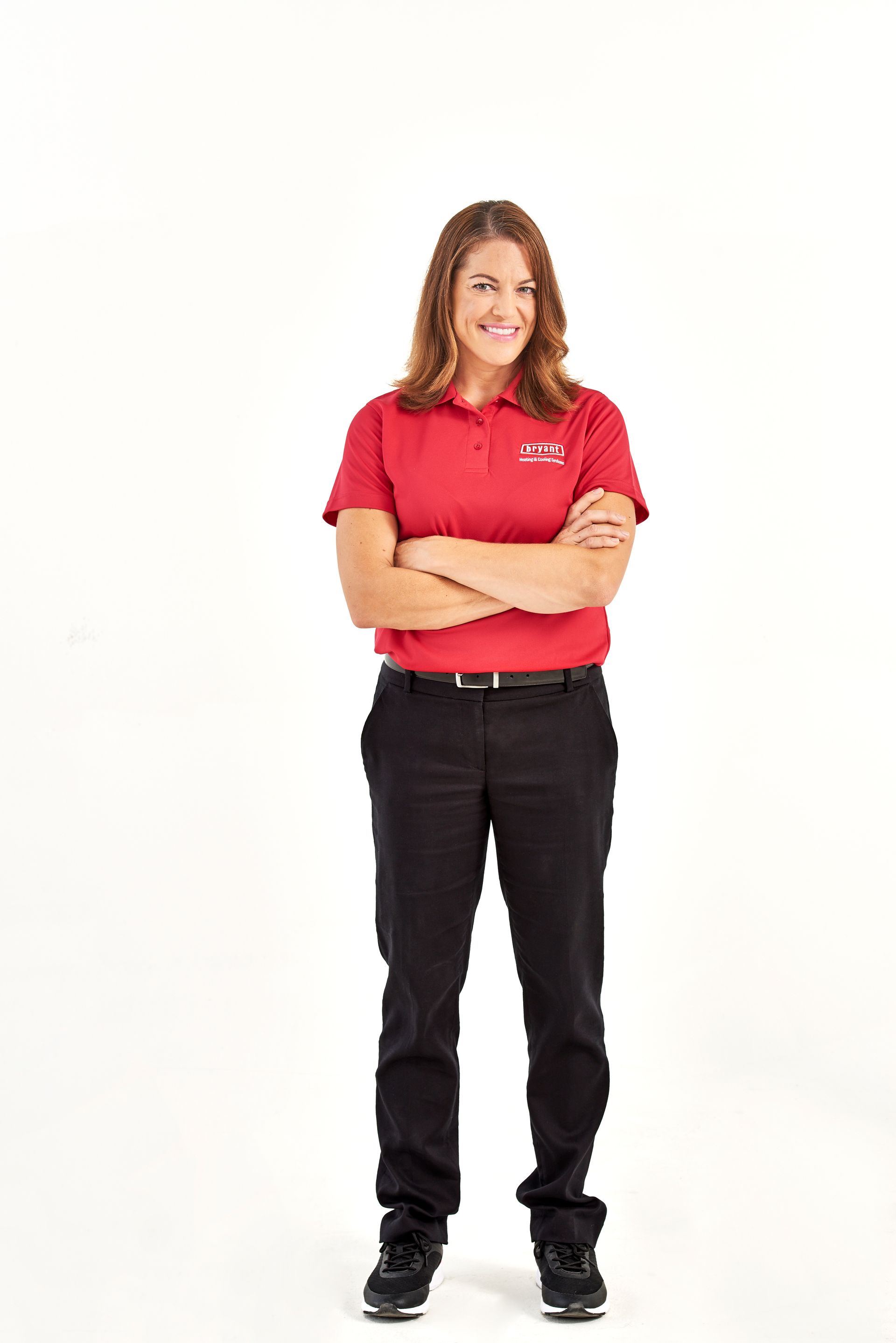 A woman in a red shirt and black pants is standing with her arms crossed.