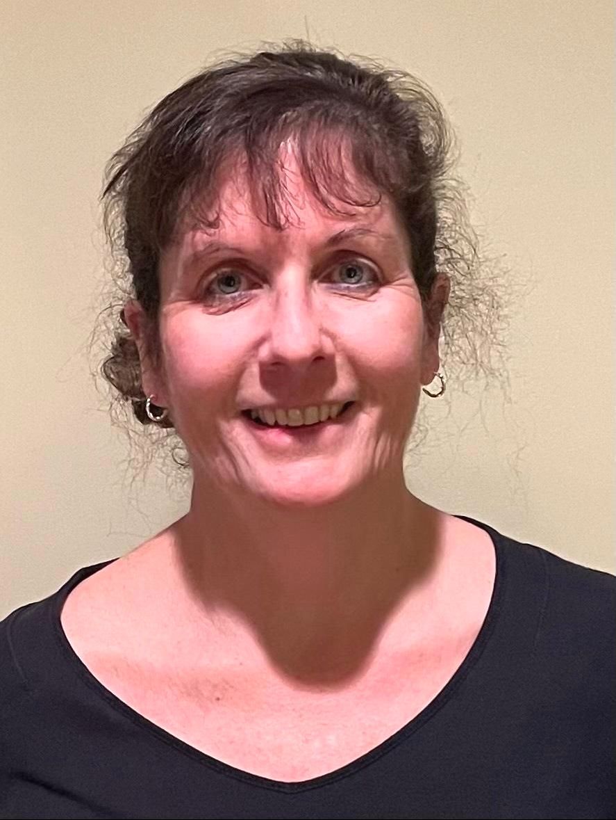 Woman with brown hair smiles, wearing a black top, against a neutral background.