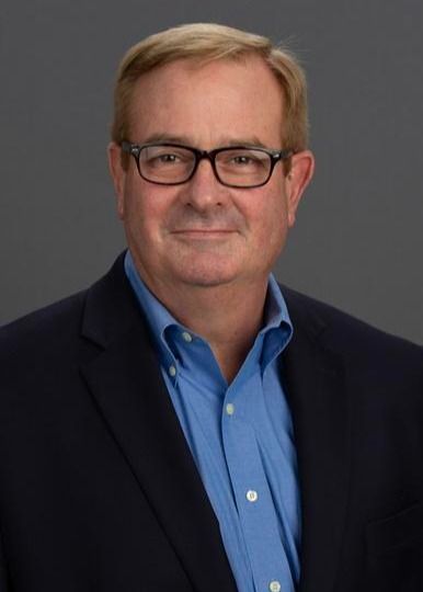 Man in glasses, blue shirt, navy blazer, looking at the viewer.