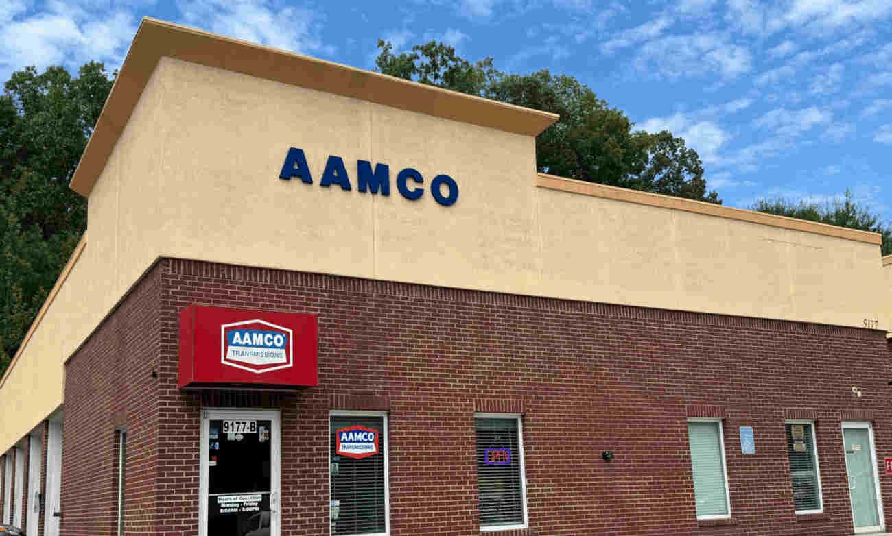 AAMCO Canton, GA - Transmission and auto repair shop with tan and brick exterior, red awning, and blue sky behind it