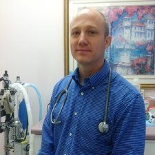 Man in blue shirt with stethoscope, in a medical office setting.