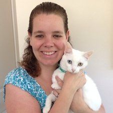 Woman holding white cat with different colored eyes; both smiling.
