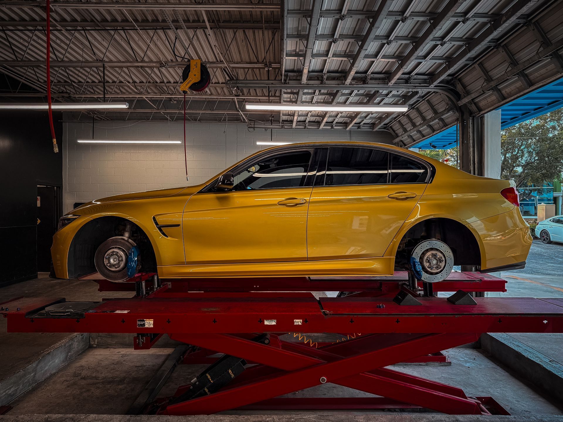 Yellow sports car on a red lift in an auto garage, side view under industrial lighting