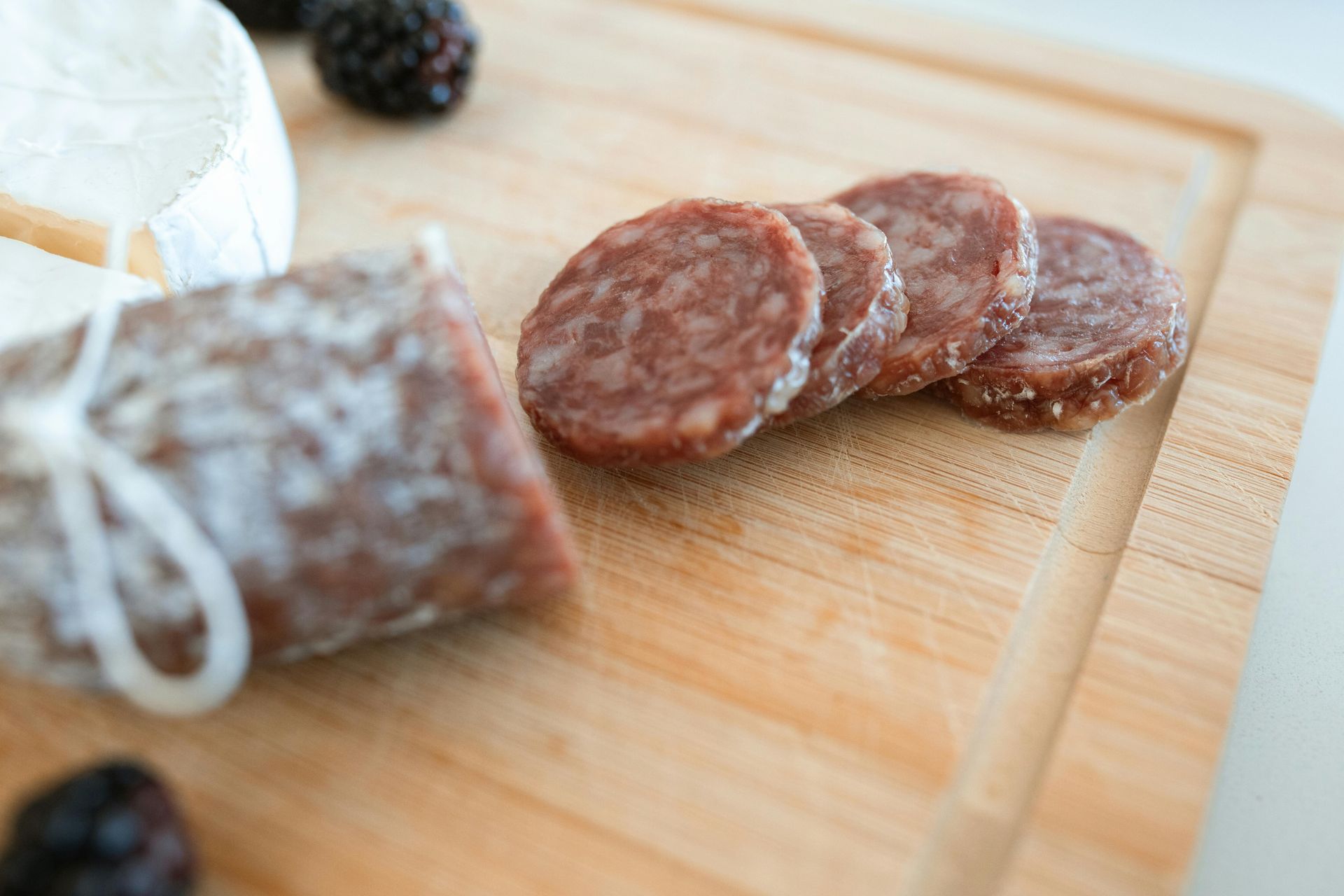 Un primo piano di salame affettato su un tagliere di legno.