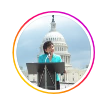 A woman is standing at a podium giving a speech in front of the capitol building.