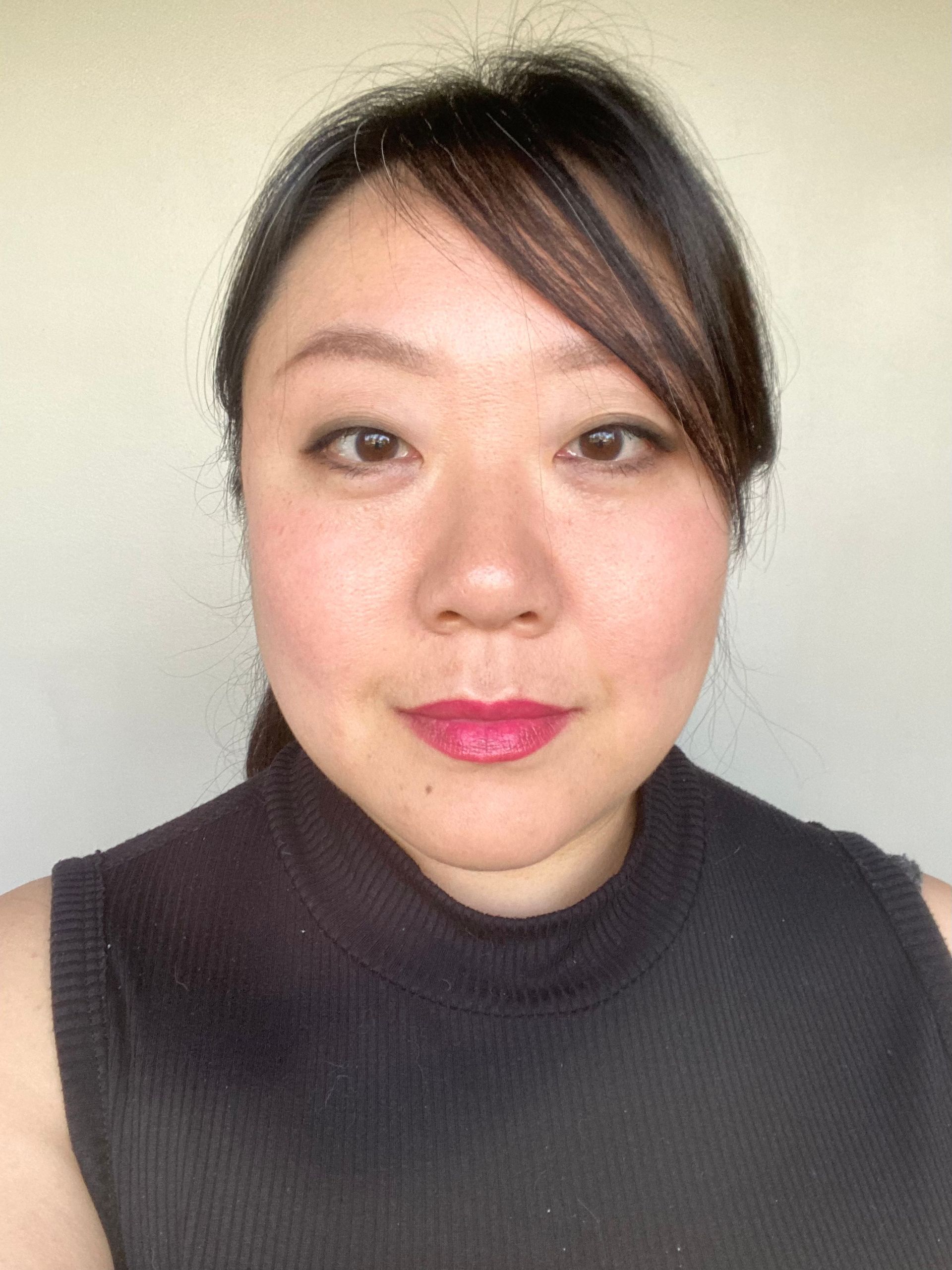 Esther Kim with dark hair and a neutral expression wears a sleeveless black top against a plain light-colored background.