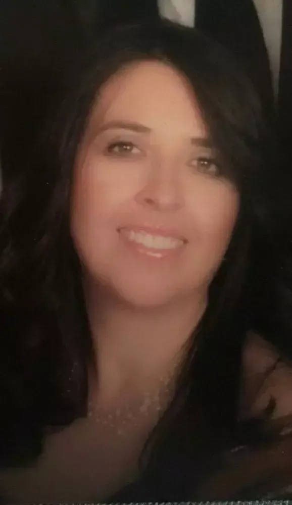 A woman with long dark hair is smiling for the camera.