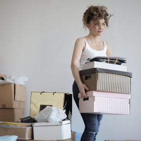 A woman is carrying a stack of cardboard boxes