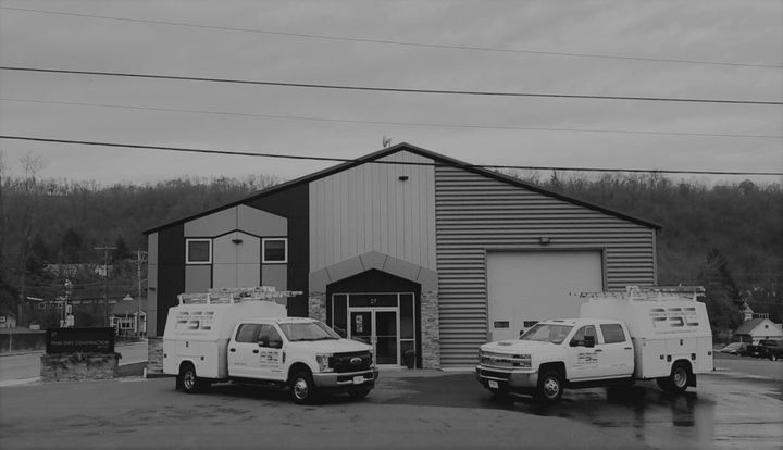 A black and white photo of two trucks parked in front of a building.