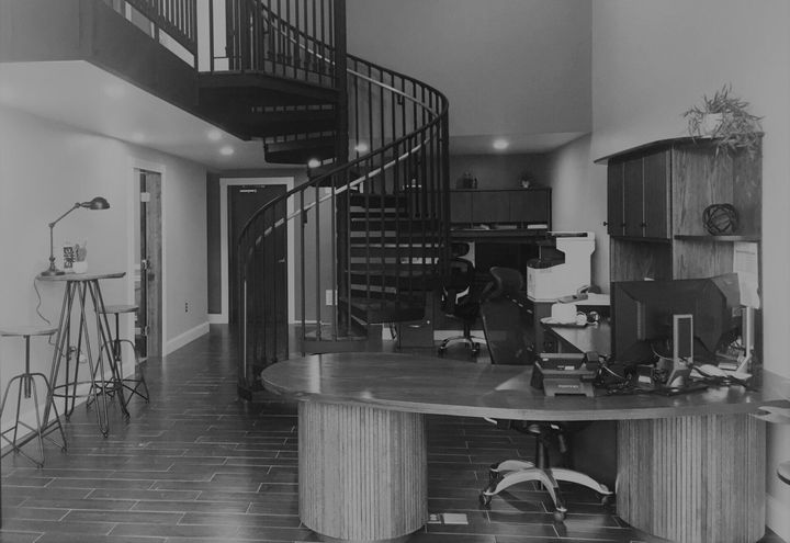 A black and white photo of an office with a spiral staircase