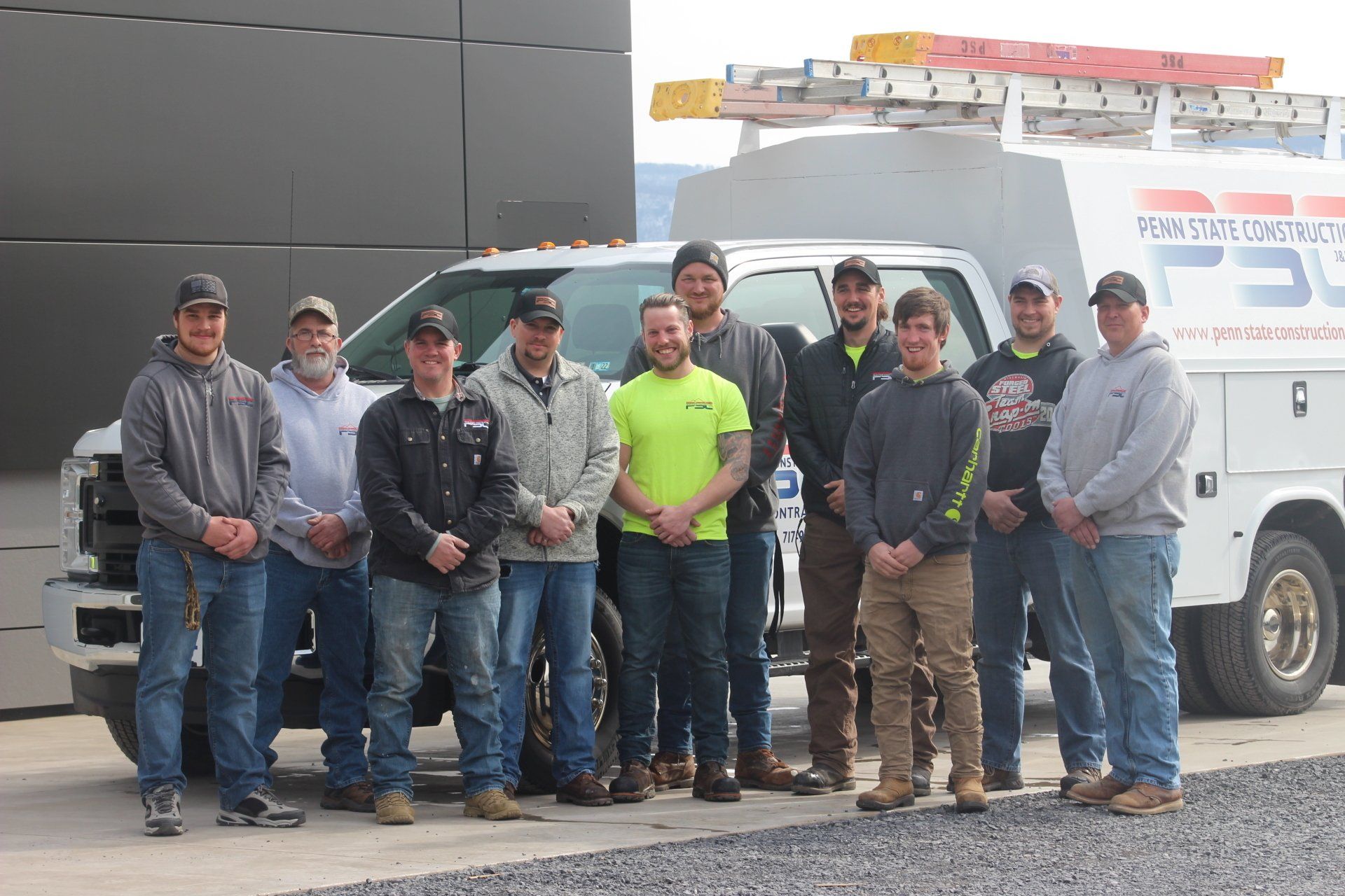A group of men are posing for a picture in front of a truck.