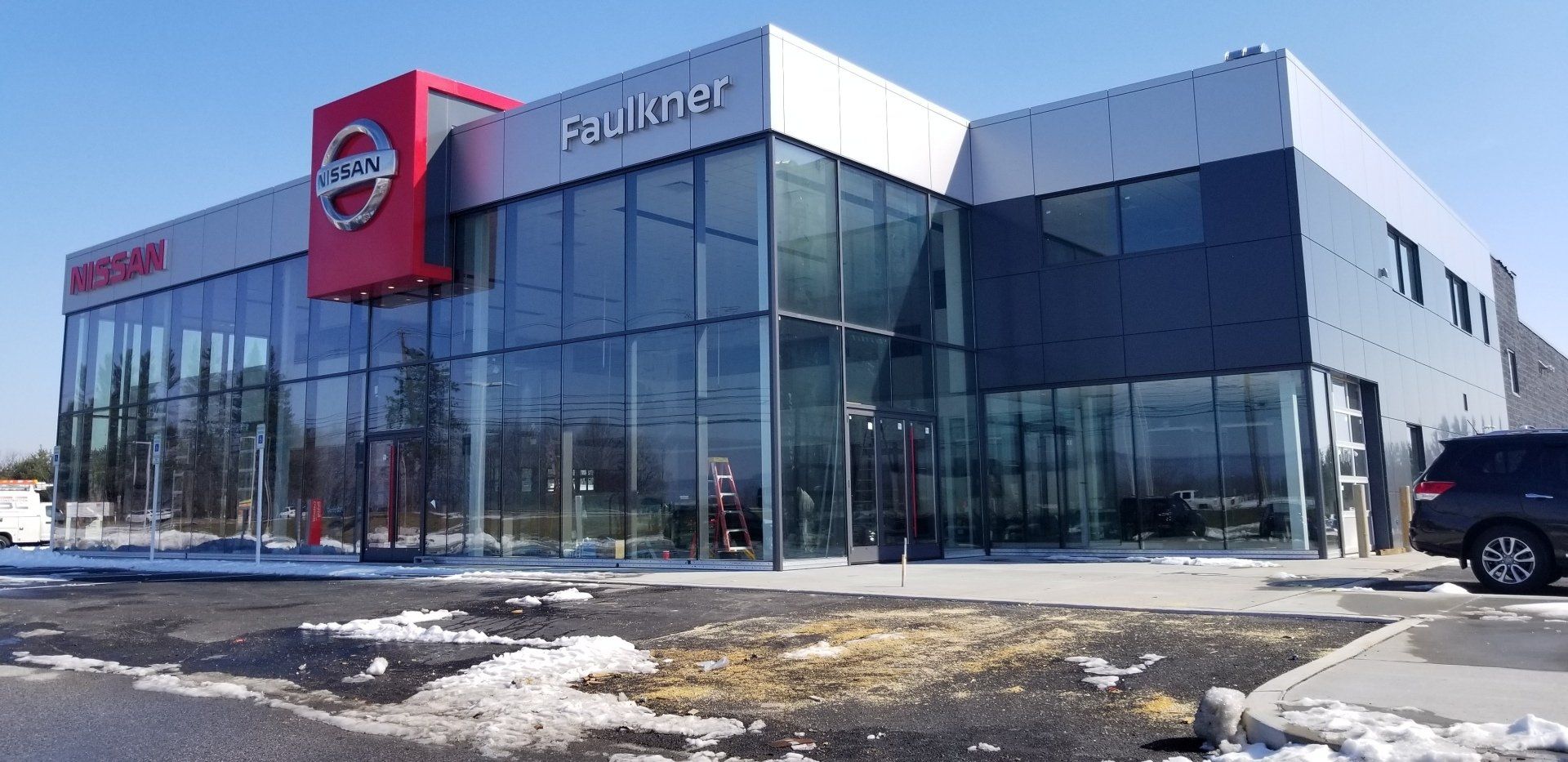 A car is parked in front of a nissan car dealership.