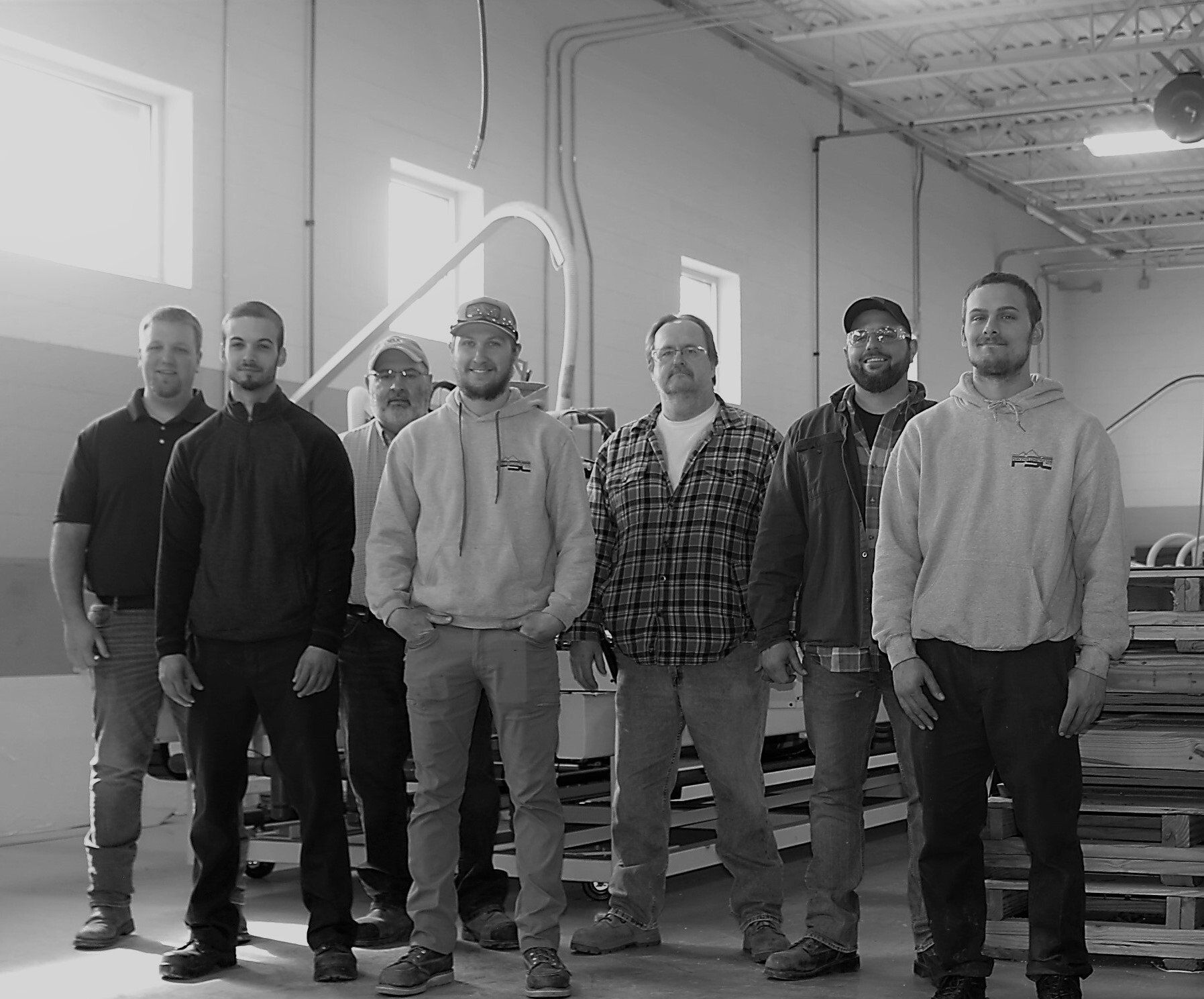 A black and white photo of a group of men standing in a room.