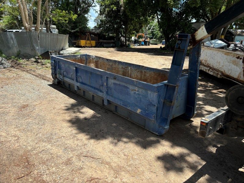 A Blue Dumpster is Parked in a Dirt Lot Next to a Truck — Bin Hire in Maryborough, QLD