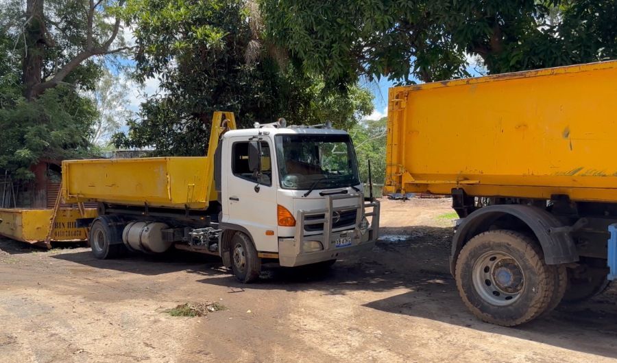 Two Dump Trucks Are Parked Next to Each Other in a Dirt Lot — Bin Hire in Maryborough, QLD
