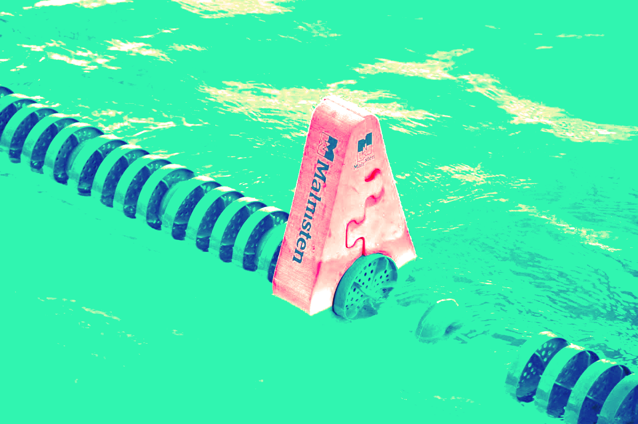 Pink swim lane divider floating in turquoise water with dark blue lane ropes on both sides