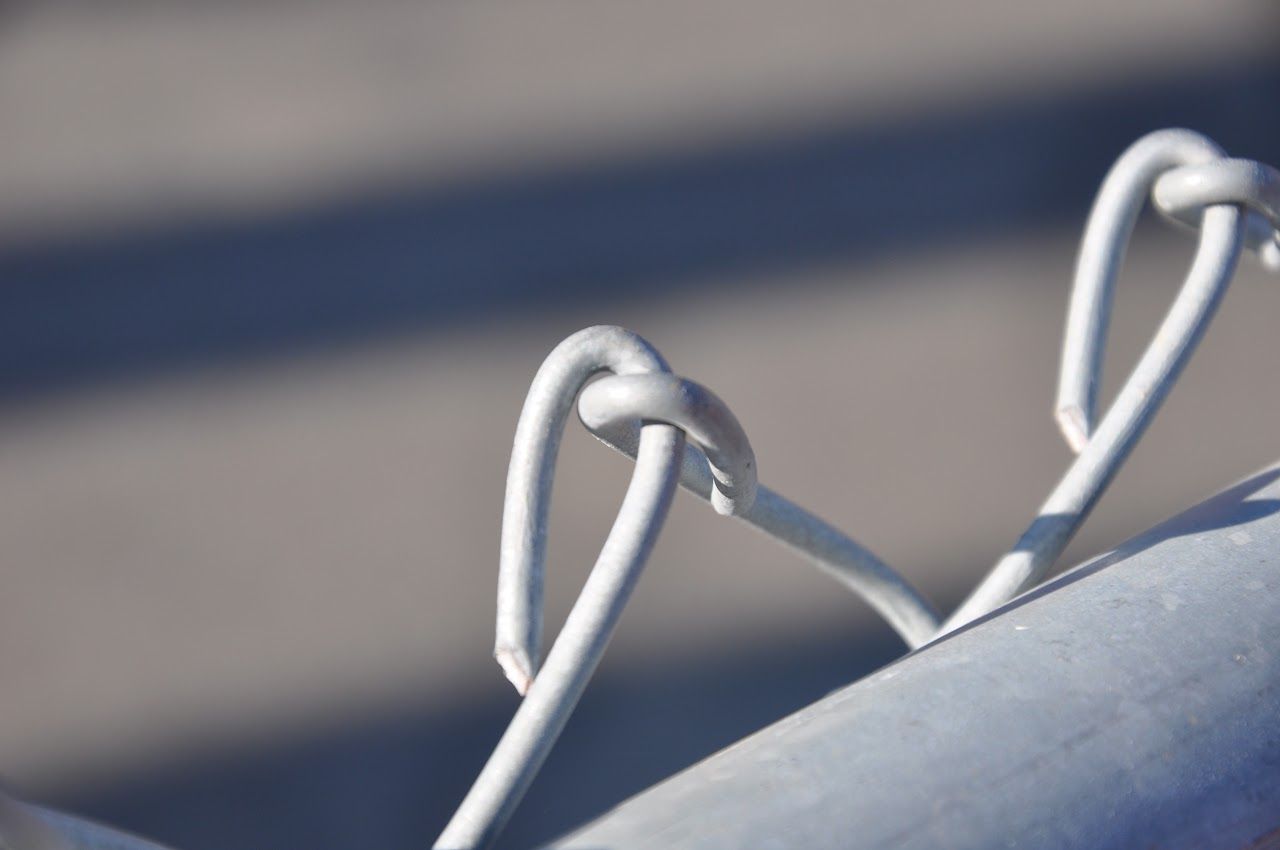 Close-up of white cords looped over a gray railing against a blurred background.
