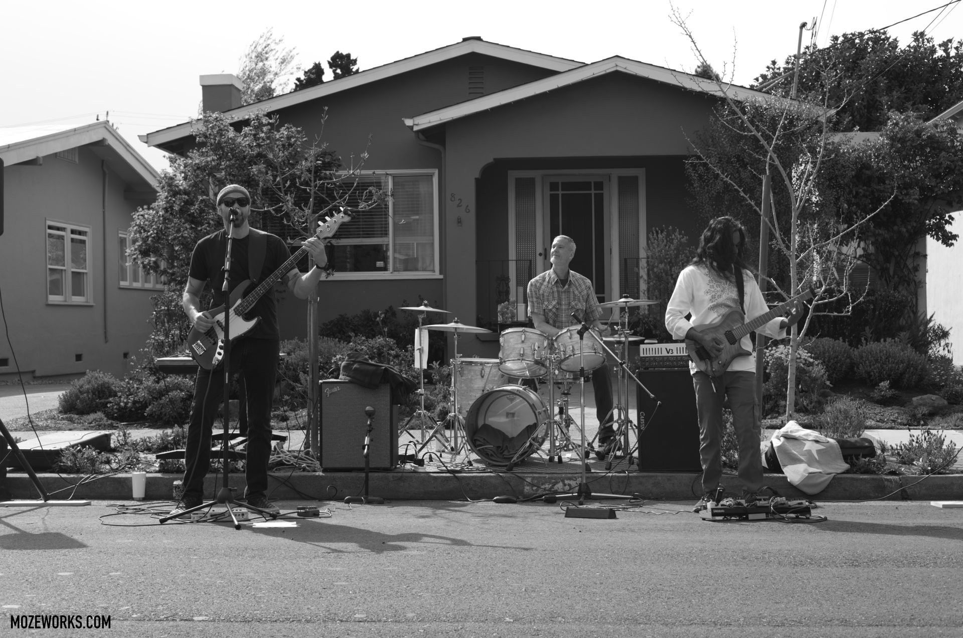 Band playing instruments in front of a house on a residential street