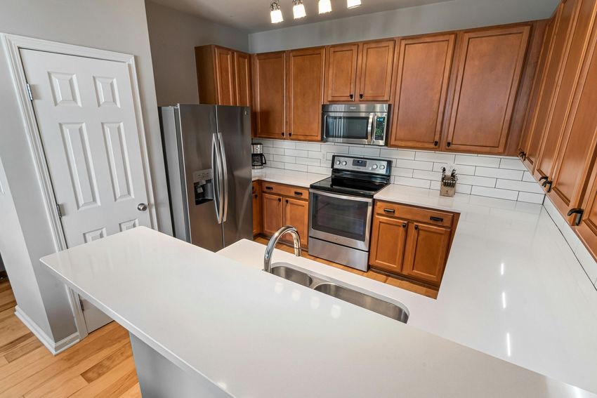 Modern kitchen with wood cabinets, stainless steel appliances, and a white island countertop