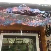 Colorful fish mural painted on an awning above a window with string lights