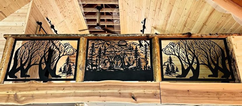 Three framed forest silhouettes hanging on a wooden wall under a ceiling vent.