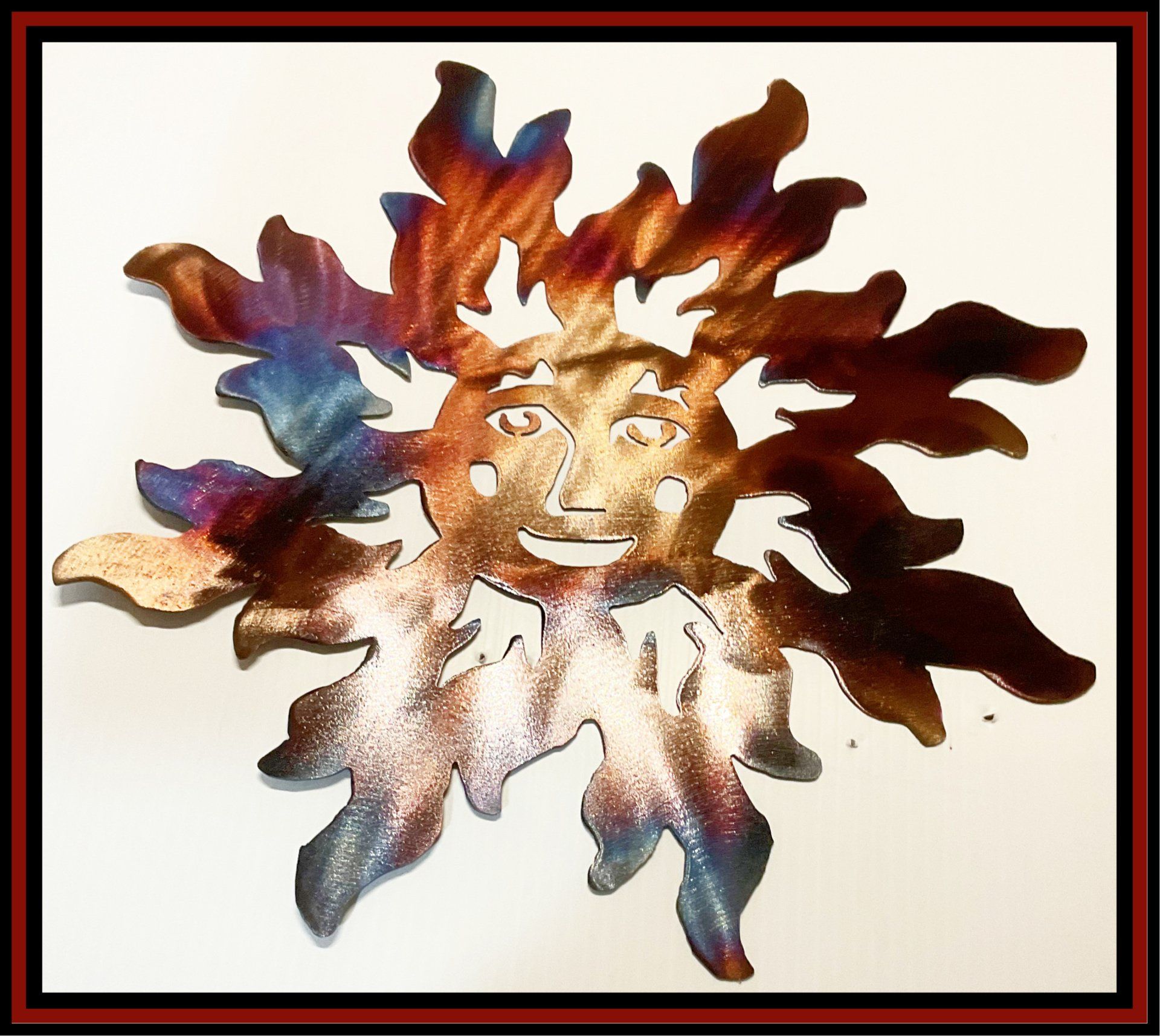 Colorful abstract sun face with leaf-like rays on a light background inside a red-and-black border