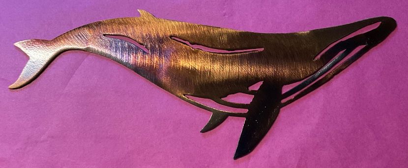 A sleek black and gold whale-shaped sculpture on a purple background