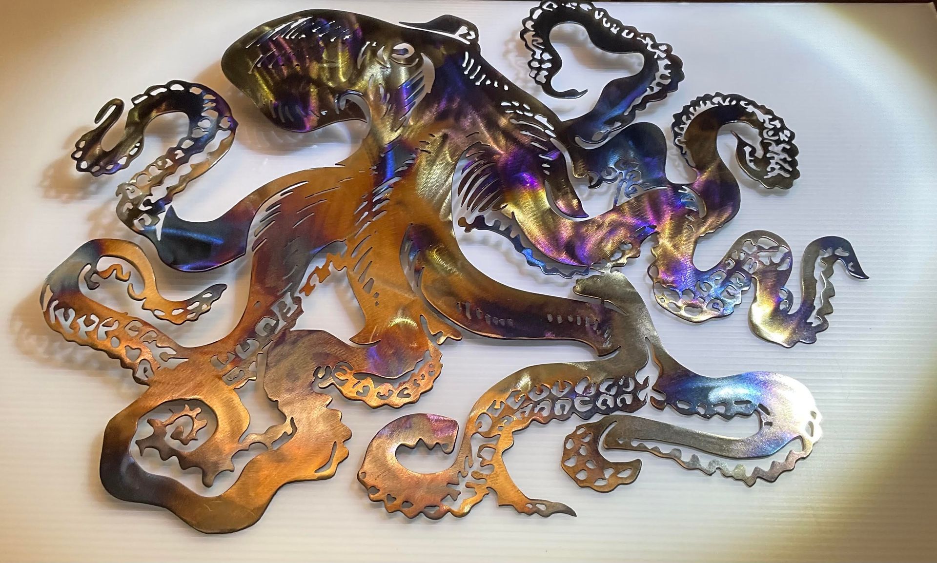 Colorful iridescent octopus-shaped art piece with curling tentacles on a light background