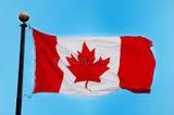 Canadian flag waving on a pole against a blue sky