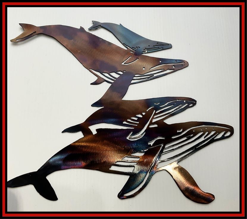 Metal wall art of three overlapping dolphins in brown, blue, and black on a white background