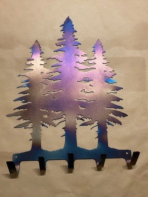 Metal pine tree silhouette with purple-blue gradient on a beige background, standing on small feet