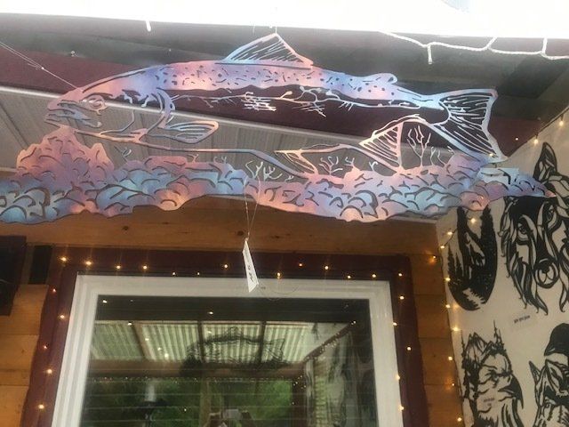 Neon fish mural above a doorway, with string lights and black-and-white face illustrations on the wall