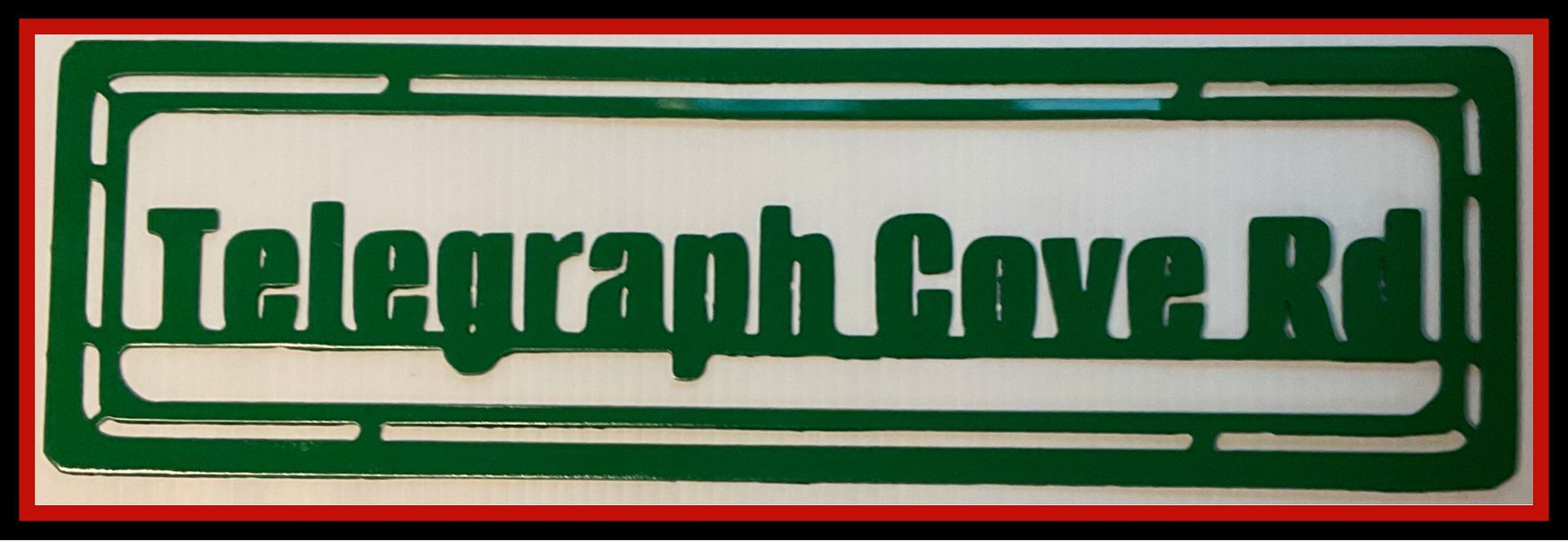 Green street sign reading “Telegraph Cove Rd” on a white background with a red border